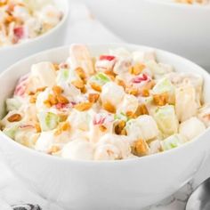 two white bowls filled with fruit salad on top of a table