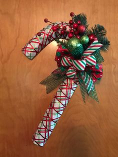 a christmas decoration with candy canes and ornaments on it's side, sitting on a wooden surface