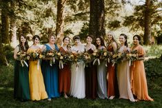 a group of women standing next to each other holding bouquets in front of trees