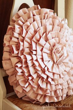 a large pink ruffled pillow sitting on top of a chair