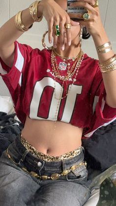 a woman in a football jersey taking a selfie with her cell phone while sitting on a bed