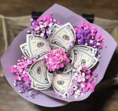 a bunch of money is sitting on top of a bouquet of flowers with pink and purple flowers