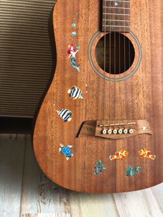 an ukulele with stickers on it sitting in front of a speaker system