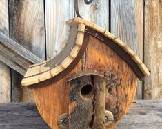 a birdhouse made out of wood with a metal hook on the front and side