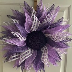 a purple and white mesh sunflower is hanging on the front door with it's center piece