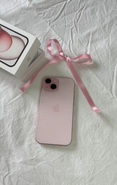 an iphone case with a pink ribbon tied around it and a box next to it