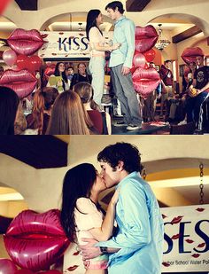 a couple kissing each other in front of red balloons and kiss signs at a party