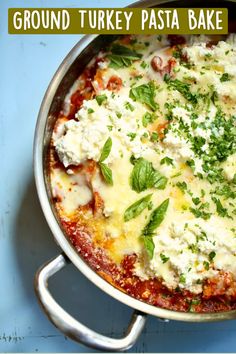 a close up of a pizza in a pan with cheese and herbs on the top