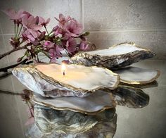 a candle that is sitting on some kind of rock with flowers in the back ground