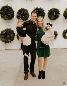 a man, woman and two children posing for a photo in front of wreaths