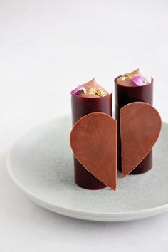 two pieces of chocolate sitting on top of a white plate with a heart cut out