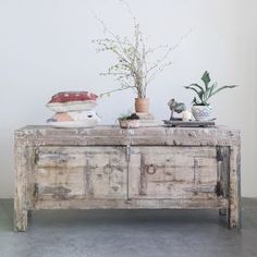 an old wooden table with some plants on top