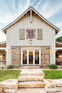 a large white barn with stone steps leading up to the front door and side windows