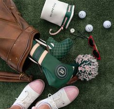 shoes and accessories laid out on the grass next to a purse, golf balls, and other items