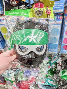 a person is holding up a plastic mask in front of some other items at a store