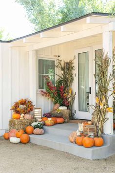 the front porch is decorated with pumpkins and flowers