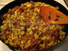 a skillet filled with food sitting on top of a stove next to an orange spatula