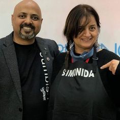 two people standing next to each other in front of a sign with the words siminda on it