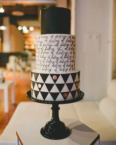 a three tiered cake with black and white designs on the top is sitting on a table