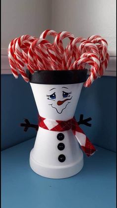 a snowman made out of candy canes sitting on top of a blue table