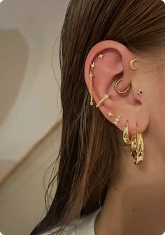 a woman wearing gold ear cuffs with stars on them