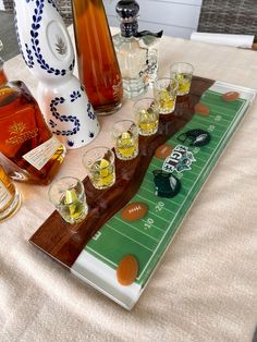 a table topped with bottles and glasses filled with alcohol next to an american football field