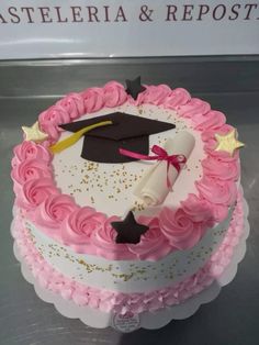 a pink and white cake with a graduation cap on top that is decorated with gold stars