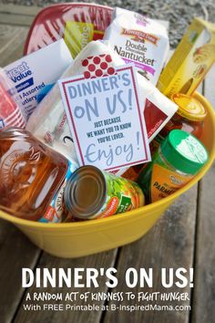 a yellow bowl filled with food on top of a wooden table next to a sign that says dinner's on us - a sharemeal random act of kindness