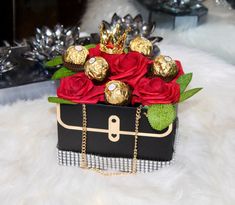 a black box with red roses and chocolates in it sitting on a white furnishing