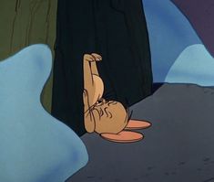 a cartoon character laying on the ground in front of a cave