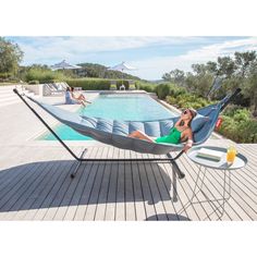 a woman laying in a hammock next to a swimming pool