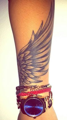 a woman's arm with a bird tattoo on it and some bracelets around her wrist