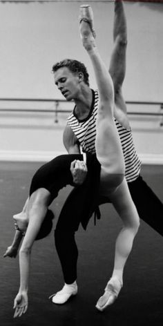 two people are doing acrobatic tricks on the dance floor in black and white