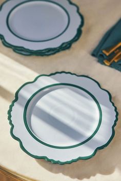 two plates sitting on top of a table next to each other with green trim around the edges