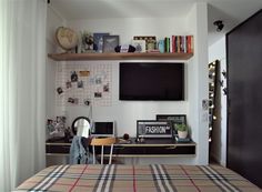 a bedroom with a bed, desk and television mounted on the wall over it's headboard