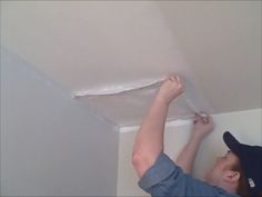 a man is painting the ceiling with white paint