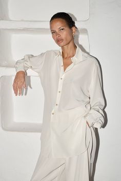 Oversized and relaxed fit. Shirt Collar Curved front and back hem. Back of the shirt fits longer than the front. Exposed Buttons. Mother pearl buttons. French seam finish Fits comfortably across shoulders, falls loose throughout the body. Oversized full-length sleeves with pleats and mother pearl button cuffs. Full-length sleeves with pleats and button cuffs Colour: Nata (Cream) One Size fits S/M/L Model is 1´82 - 5’10" Unisex 100% Pure Silk. Crepe de ChineMADE IN SPAIN Elegant Oversized Blouse With Shirttail Hem, Timeless Long Sleeve Blouse With Button Cuffs, Elegant Oversized Button-up Shirt, Oversized Blouse With Button Closure For Daywear, Elegant Oversized Shirt With Button Closure, Timeless Long Sleeve Tops With Buttons, Classic Long Sleeve Shirt With Pleated Sleeves, Effortless Blouse With Button Cuffs And Shirttail Hem, Daywear Button-up Shirt With Blouson Sleeves