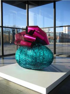 a blue and pink vase sitting on top of a white table next to a window