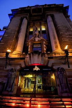 an old building lit up at night with lights on the windows and steps leading to it