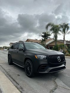 a black mercedes gle is parked in front of a house on a cloudy day