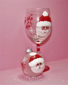 a wine glass with santa clause on it next to a christmas bauble ornament