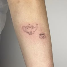 a woman's arm with a small teapot and cup tattoo on it