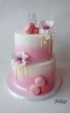 a three tiered cake with pink icing and flowers