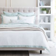 a bed with white sheets and blue pillows