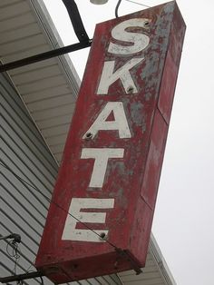 a red sign hanging from the side of a building that says skat on it