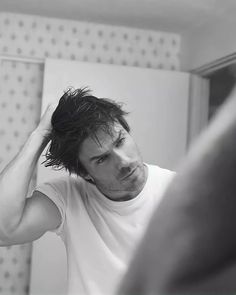 a man is looking at his reflection in the mirror while he brushes his hair with an electric razor