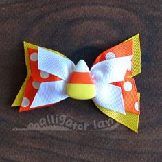 an orange, white and yellow bow with polka dots on the bottom is laying on a brown surface