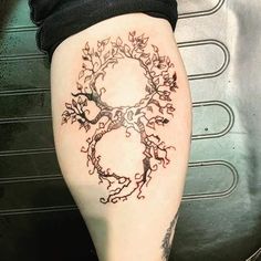 a woman's leg with a tree tattoo on the lower part of her thigh