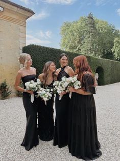 the bridesmaids are all dressed in black dresses and holding bouquets with white flowers