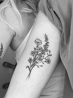 two women with tattoos on their arms, one has flowers and the other has leaves